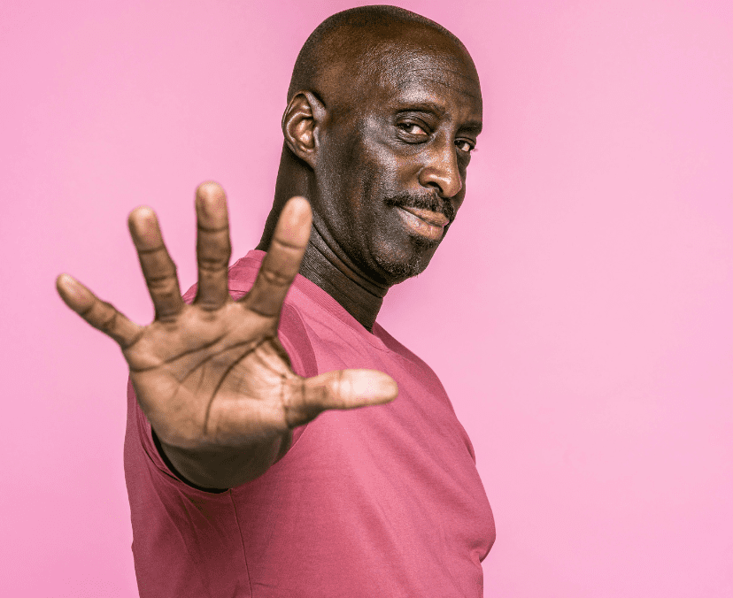 man wearing a pink tshirt holding his hand up